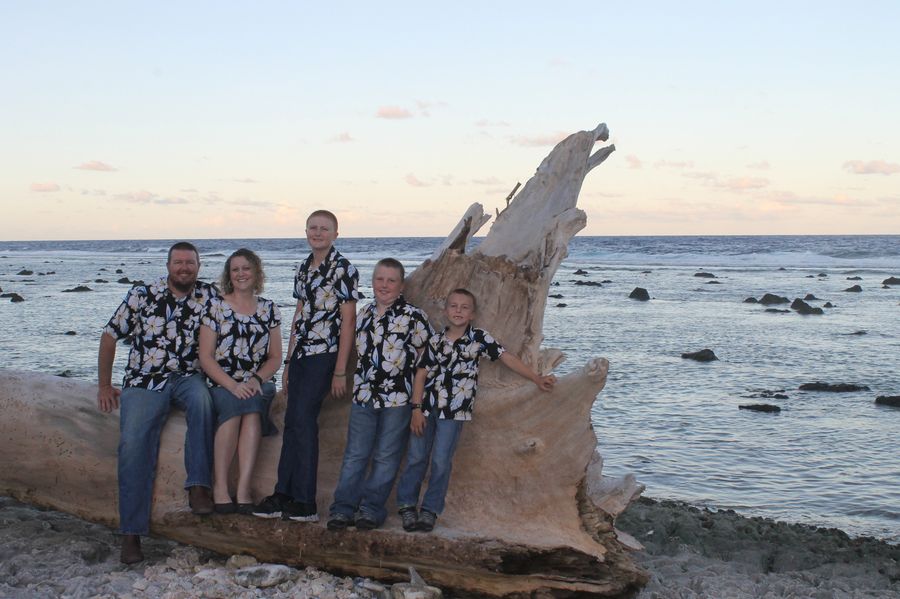 The McGeorge family sitting on a driftwood log on the shore in Nauru