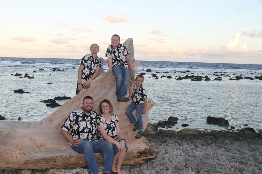 The McGeorge family on a large driftwood log on the shore in Nauru