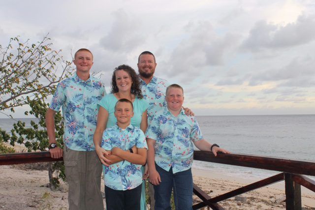 The McGeorge family by a wooden railing above the beach in Nauru